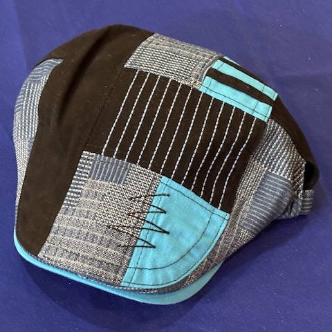 A Duckbill hat with aqua, grey and black