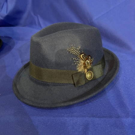 A dark trillby hat with golden coloured accessories